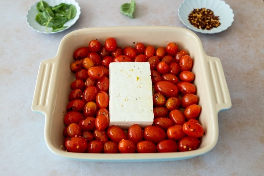 Tomatoes in a baking dish with a block of Feta cheese in the centre