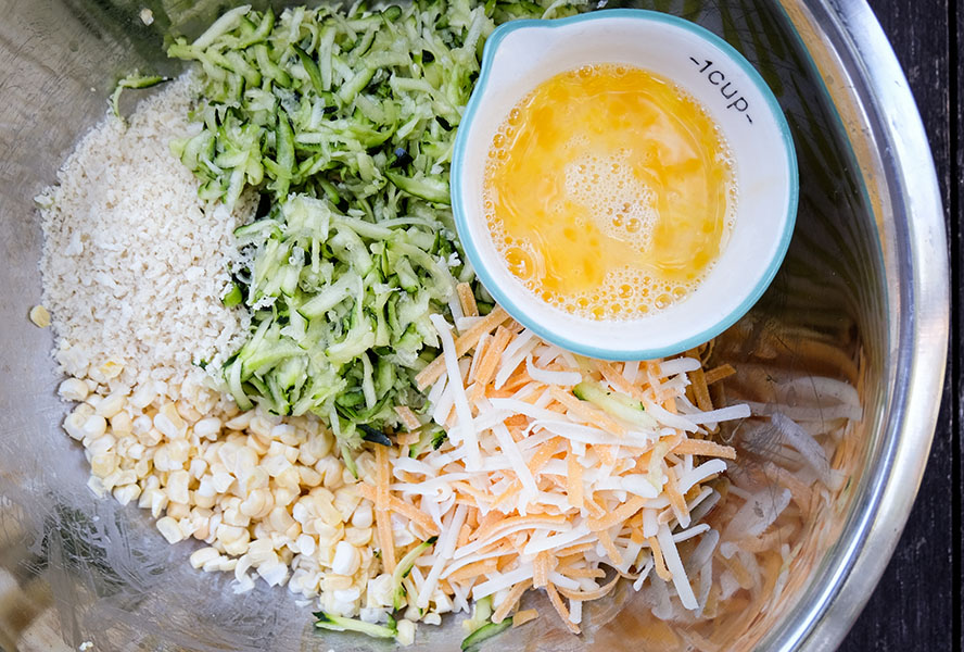 ingredients for corn and zucchini fritters in a bowl and ready to be mixed