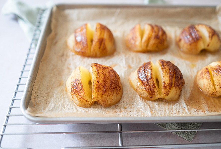 baked hasselback apples on a parchment lined baking sheet