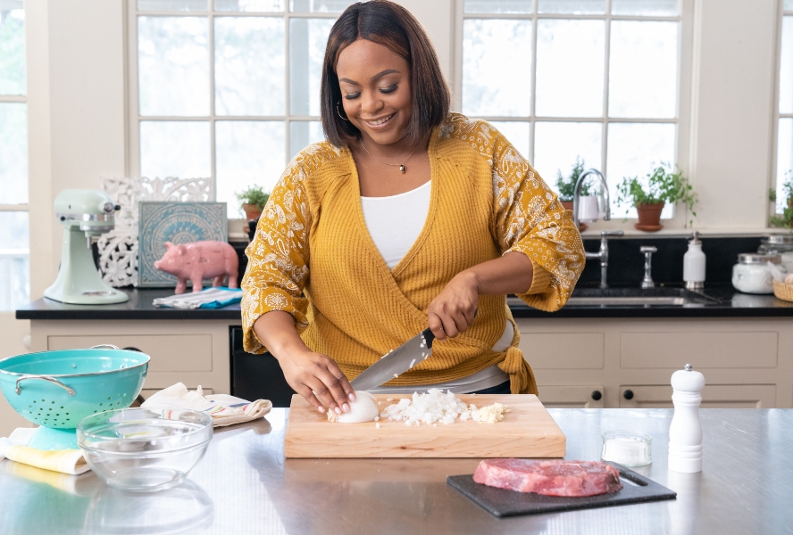 Chef Kardea Brown chops onions on a wooden cutting board