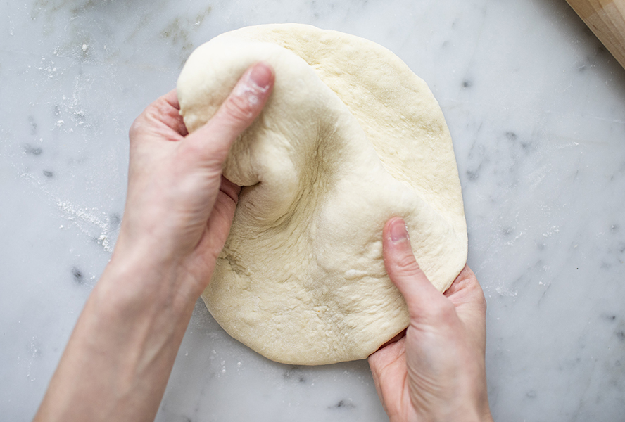 Person kneading pizza dough