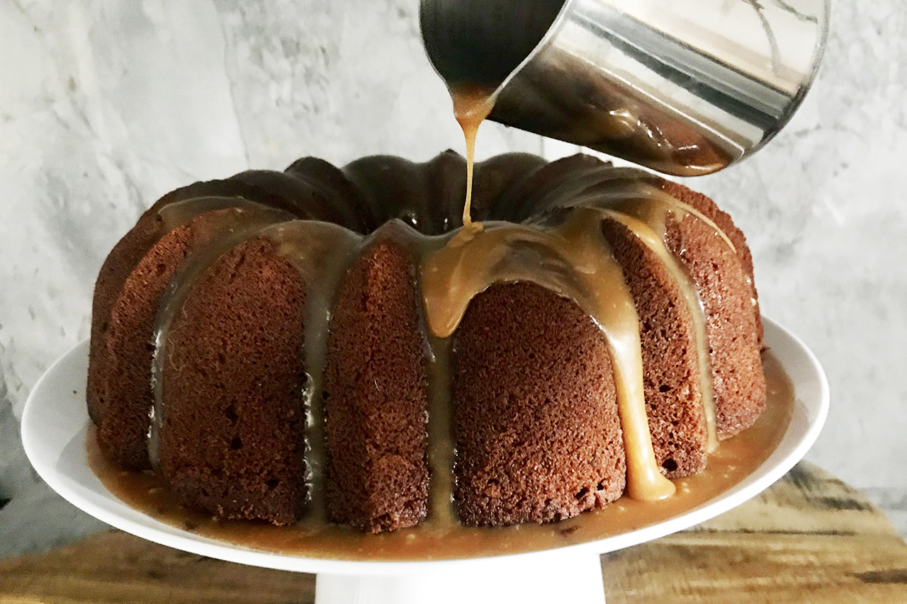 Sticky toffee bundt cake being drizzled with toffee sauce