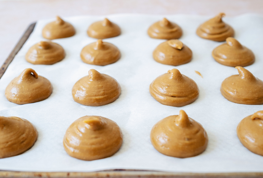 dollops of cream puff batter on a parchment lined baking sheet