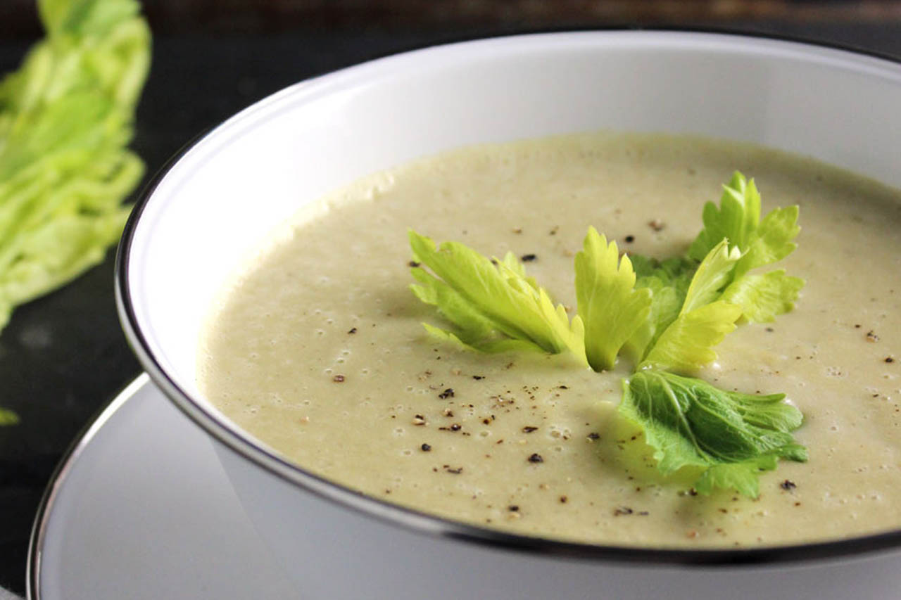 a bowl of vegan celery soup on a black countertop