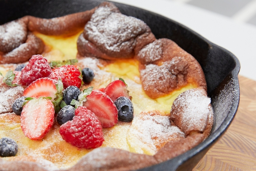 Dutch baby in cast iron skillet topped with berries