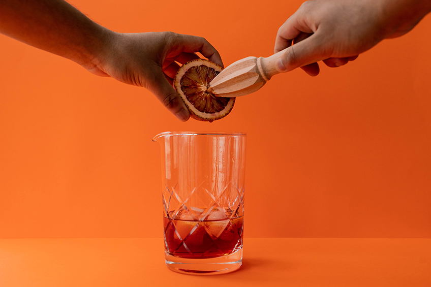 Abhishek Dekate squeezing a blood orange into a mixing glass