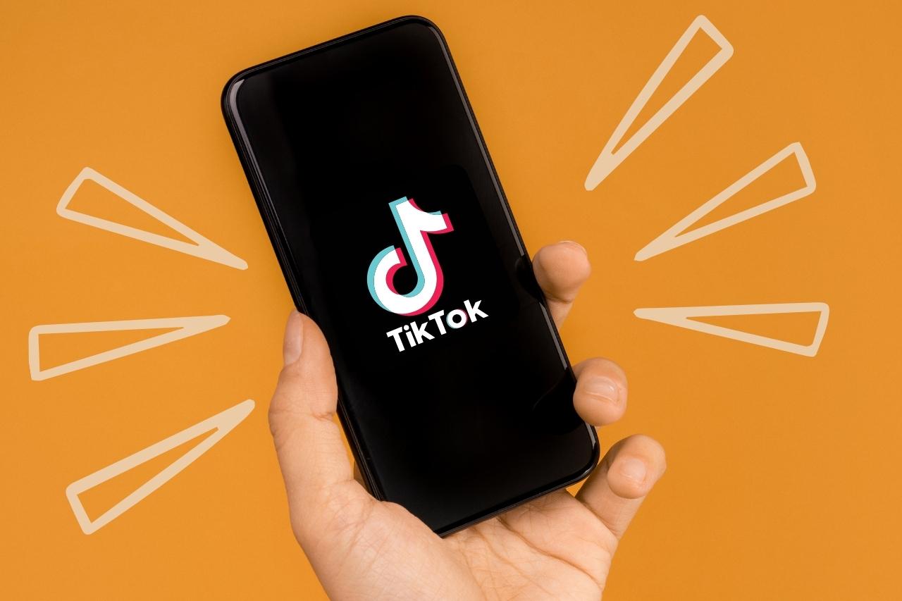 A person holding a phone with the TikTok logo
