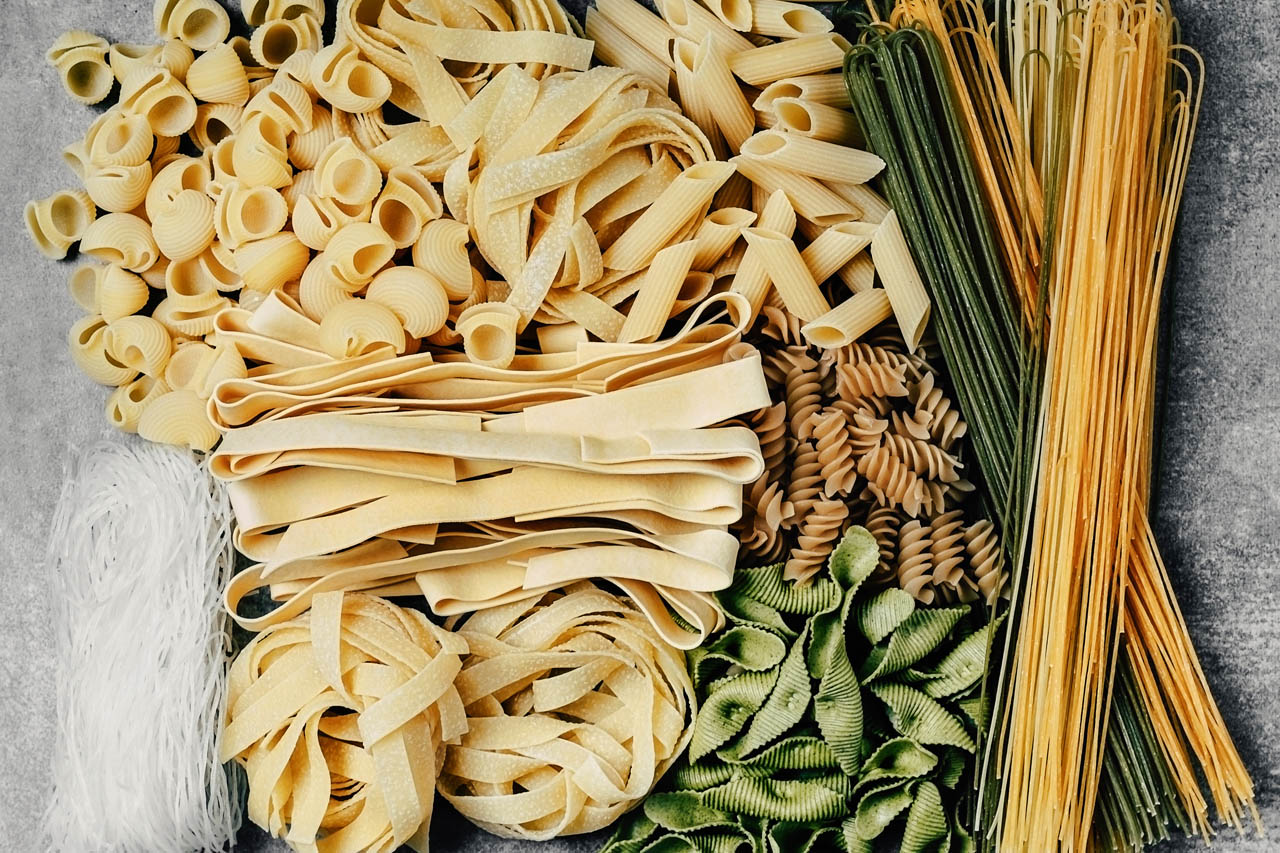 A variety of pasta shapes and sizes on a grey countertop
