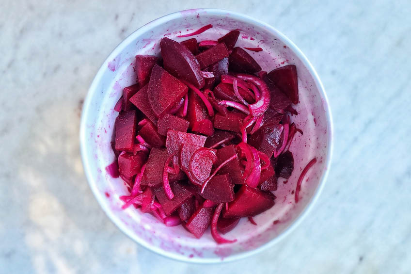 tossed beet salad in a white bowl