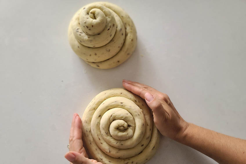two coils of dough for sephardic challah on a white countertop