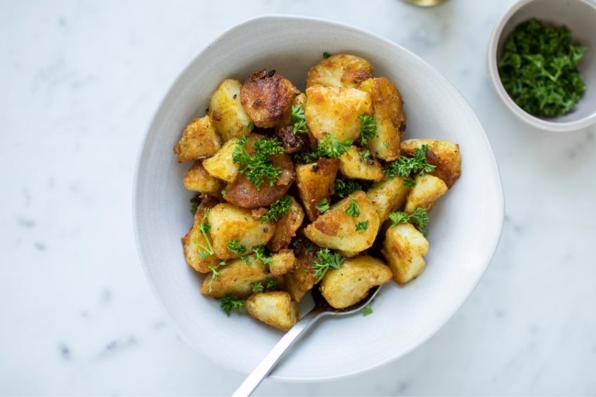 Crispy potatoes in white bowl on kitchen countertop