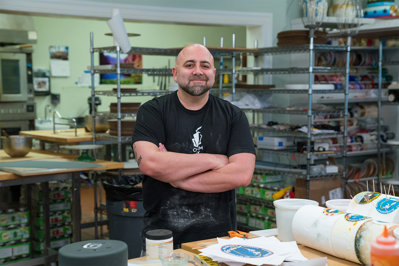 Host Duff Goldman at Charm City Cakes with his arms folder and a smile on his face