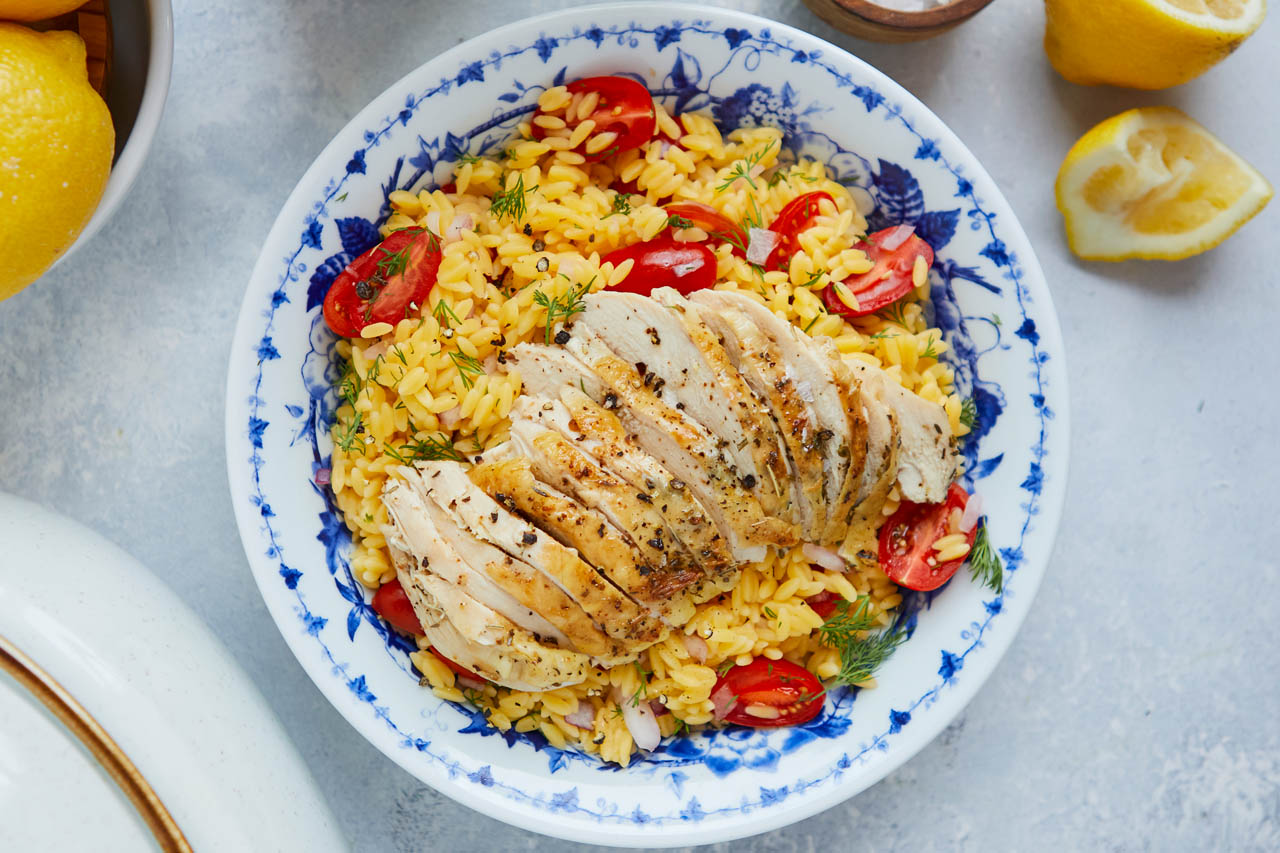 herb crusted roasted chicken with lemon garlic orzo on a blue and white patterned plate