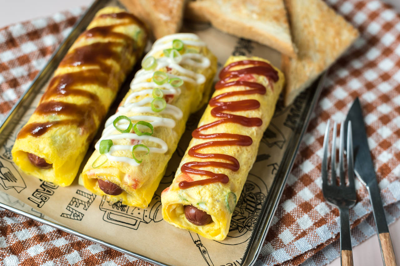 three rolled hotdog omelettes on parchment paper
