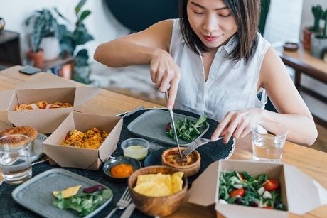Woman digging into takeout on kitchen table