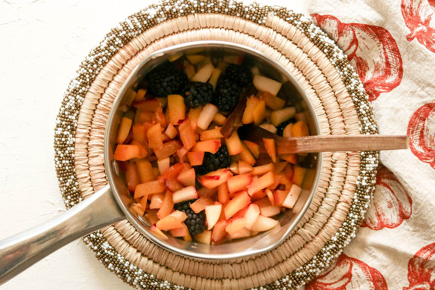 a bowl of fruit salad being tossed together