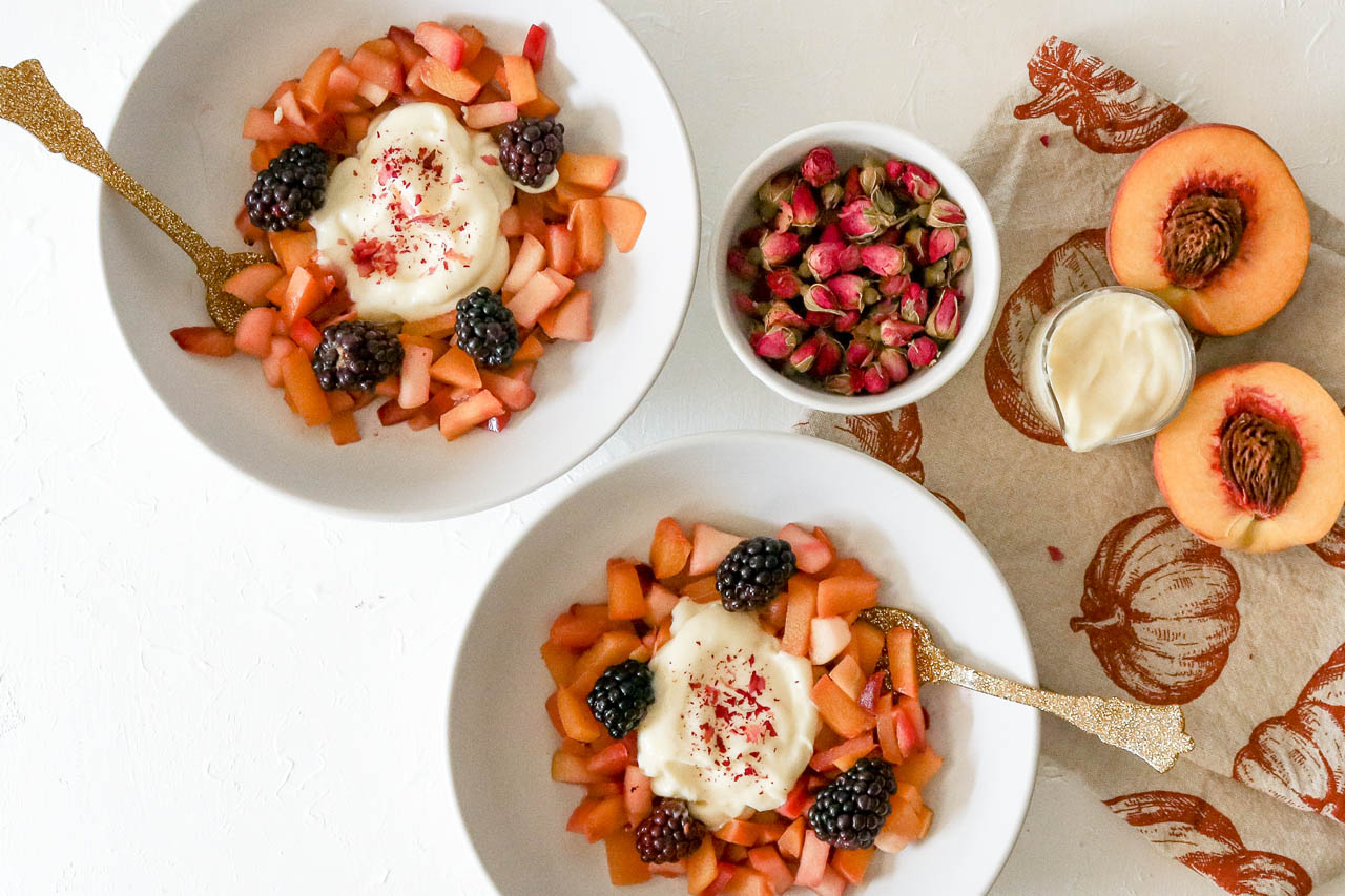 two bowls of fruit salad with rose custard on a white countertop