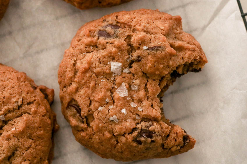 a rye chunky chocolate chip cookie on a cooling rank with a bite taken out of it