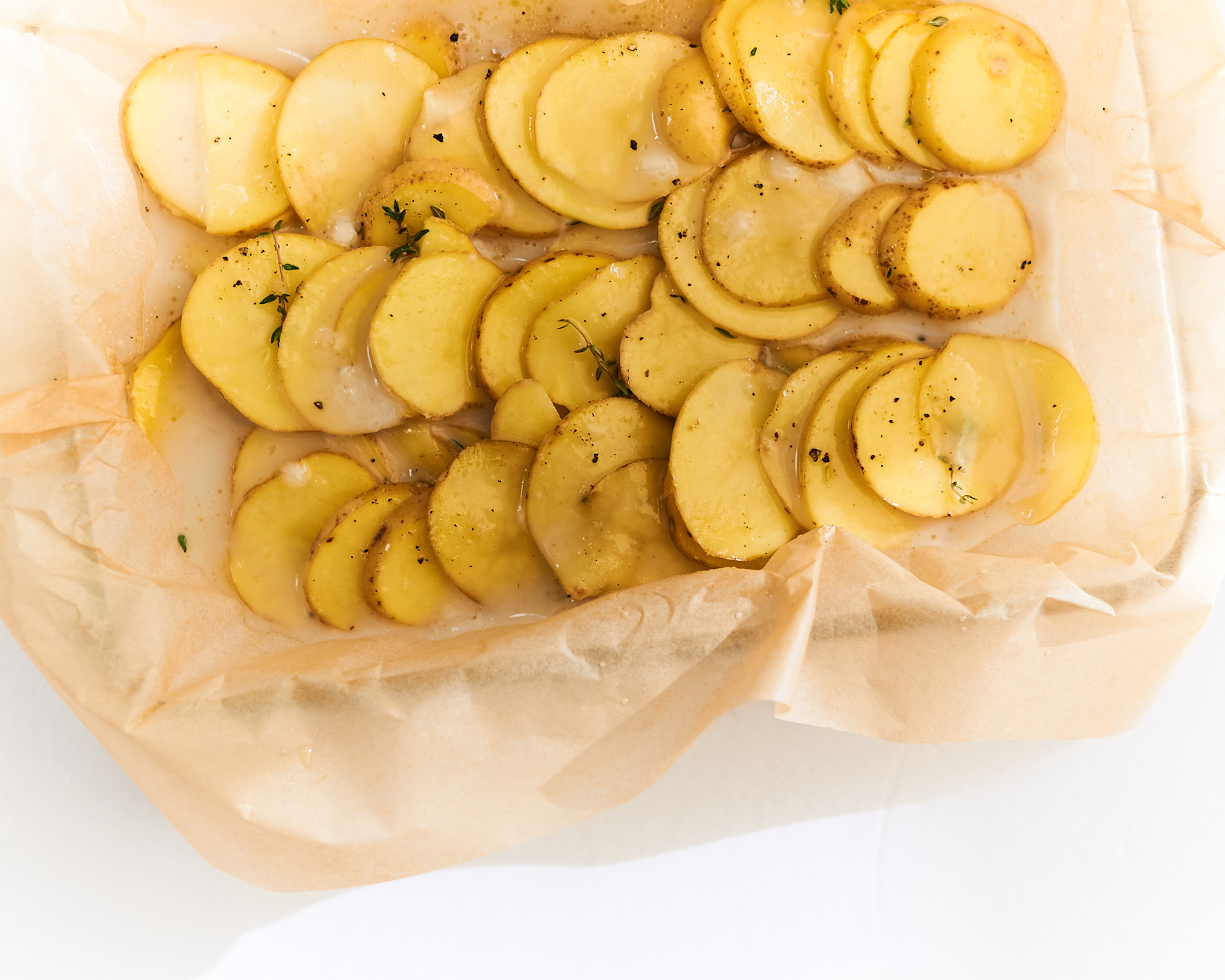 thinly sliced potatoes in a casserole dish for vegan scalloped potatoes