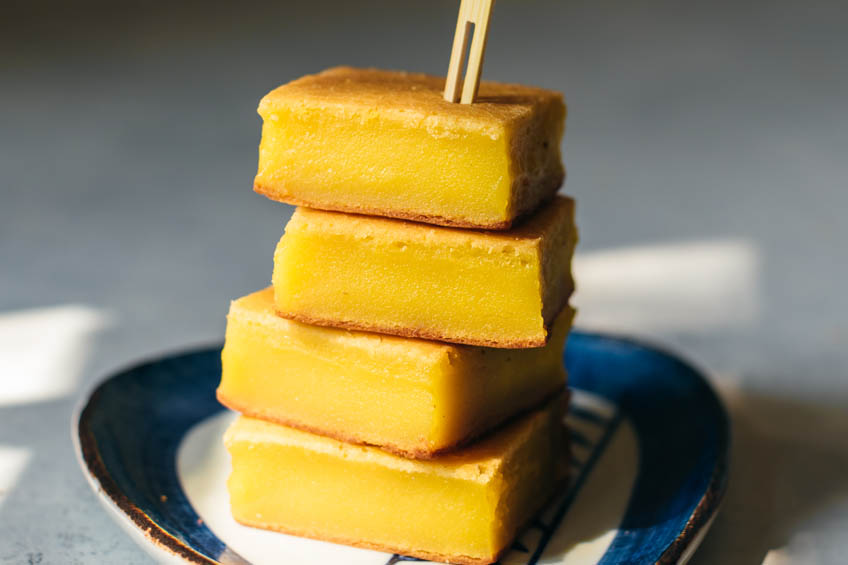 4 slices of sweet corn mochi cake piled high on a ceramic plate