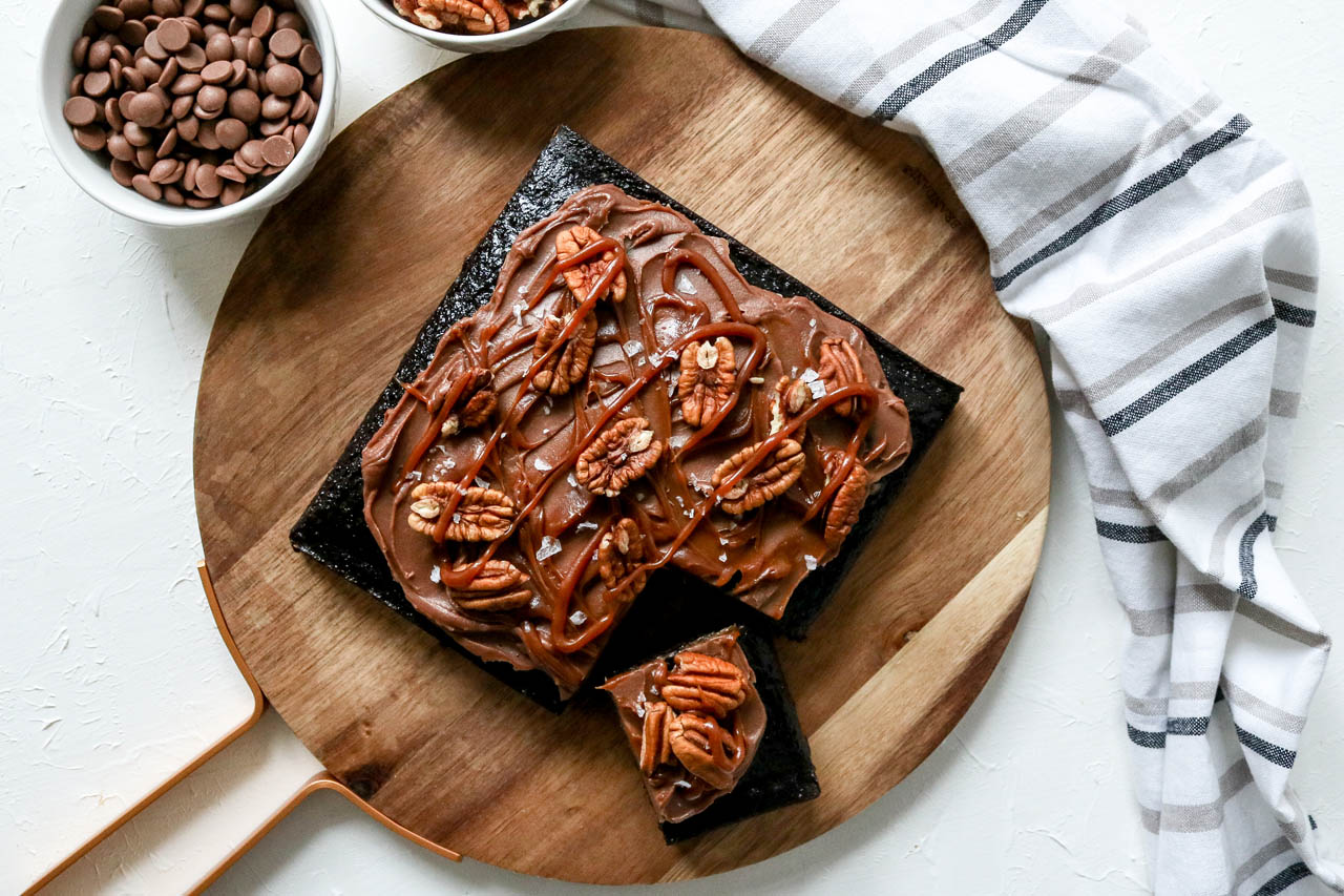 a chocolate turtle cake on a wooden serving board