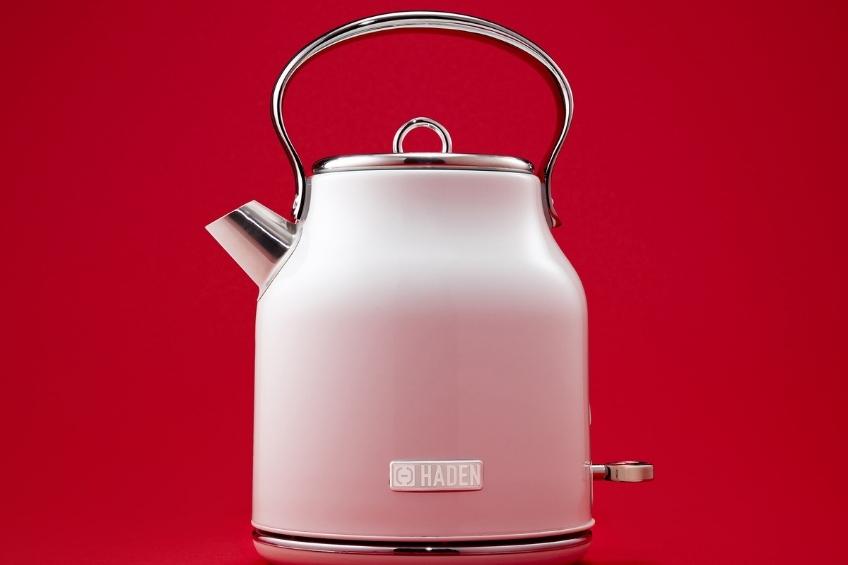 A pink electric kettle on a red background.