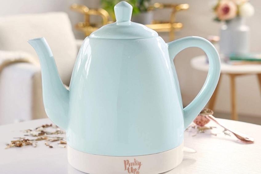 A vintage-style mint electric tea kettle on top of a kitchen table.