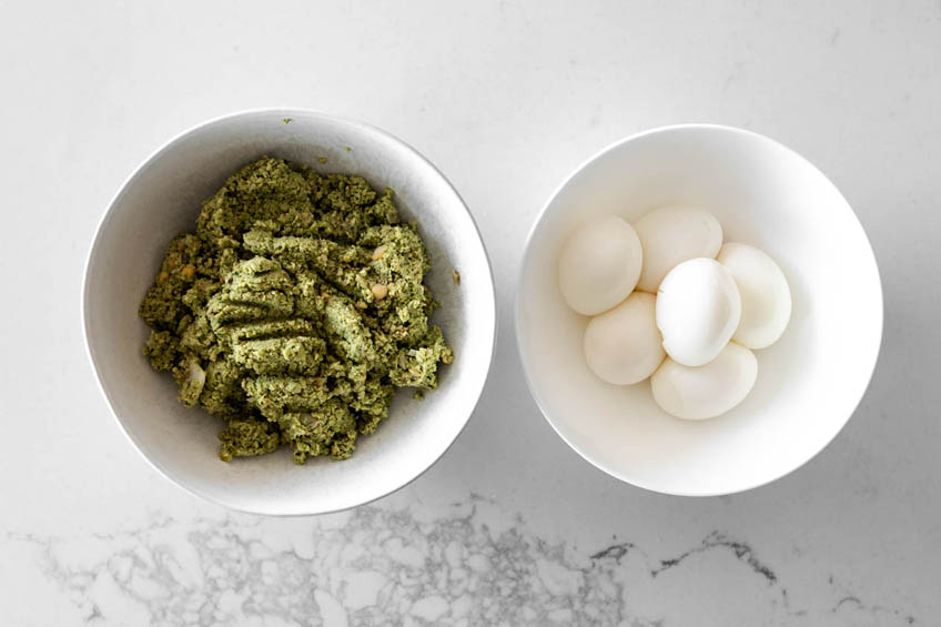 Falafel mixture and boiled, peeled eggs in two separate bowls.