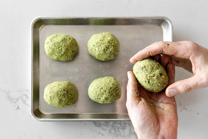 Uncooked Falafel Scotch Eggs on a baking tray.