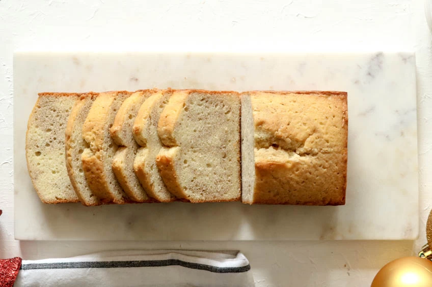 A sliced gingerbread spiced pound cake on a marble serving board