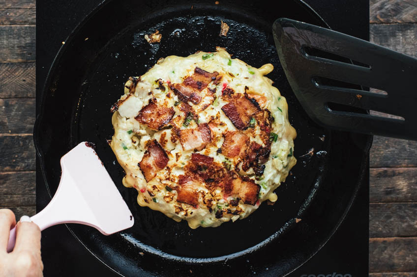 Okonomiyaki being flipped in a skillet