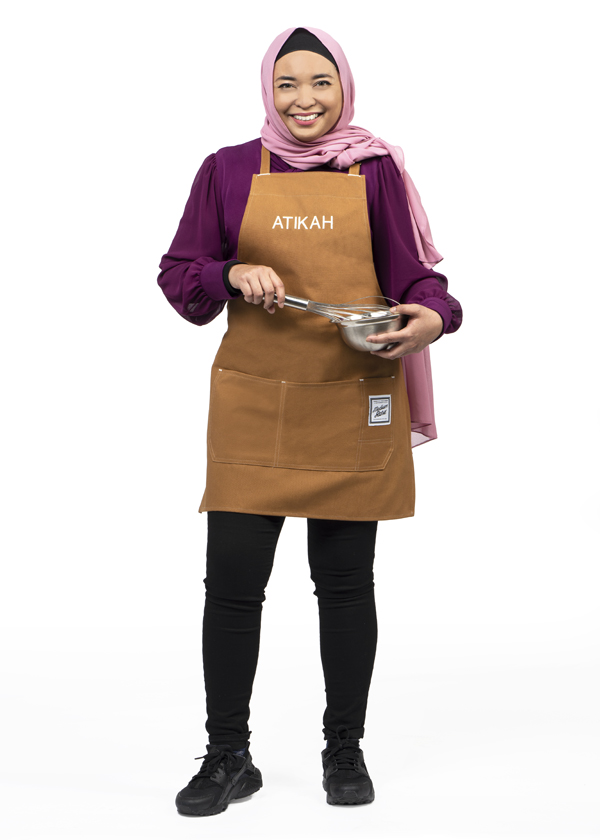 Atikah Mohamed wears black pants, a purple shirt and hijab and poses with a metal whisk and bowl