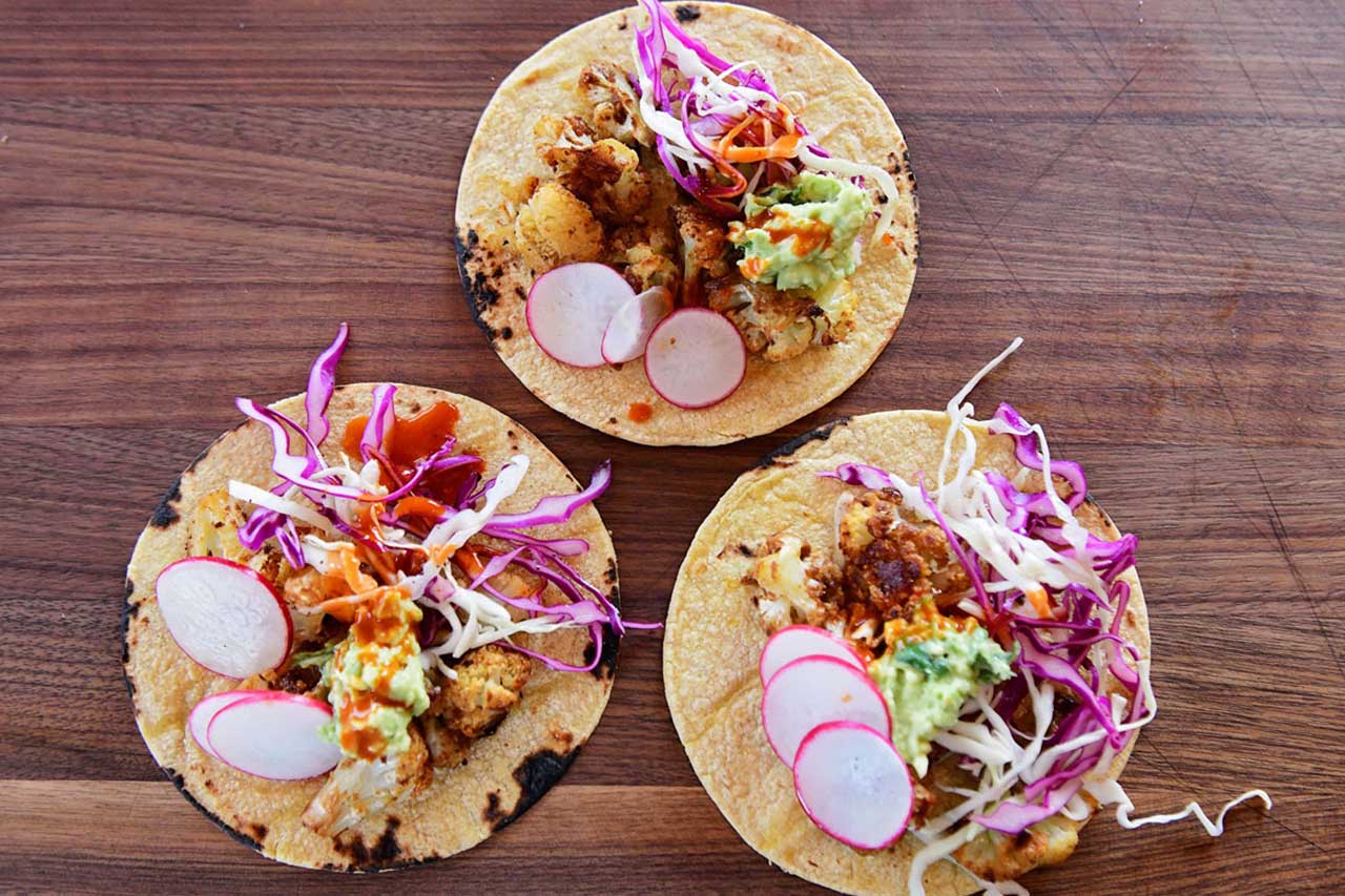 3 tacos on a wooden table overhead view
