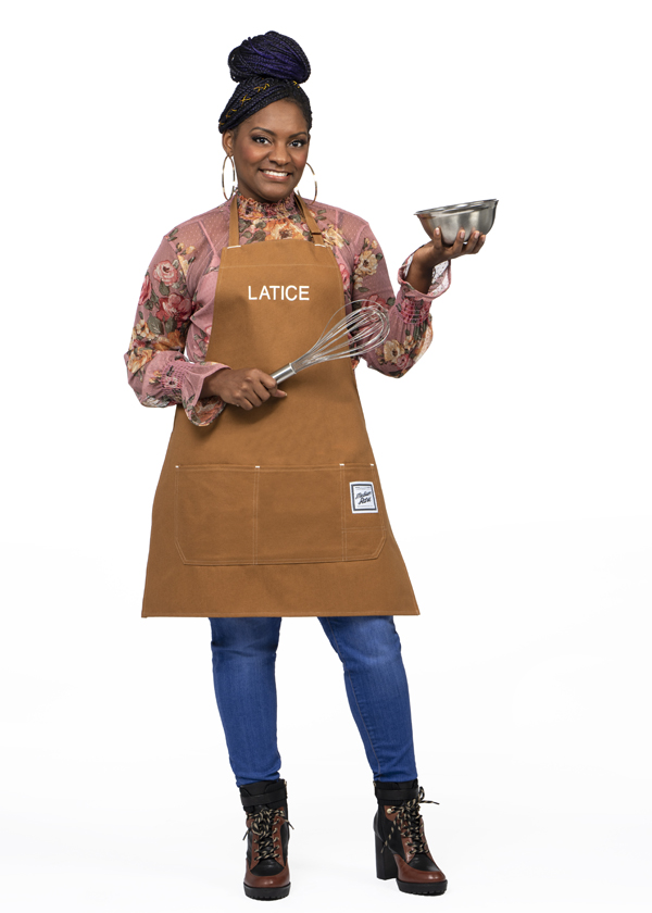 Latice Williams poses in a brown kitchen apron while holding a small metal bowl and whisk