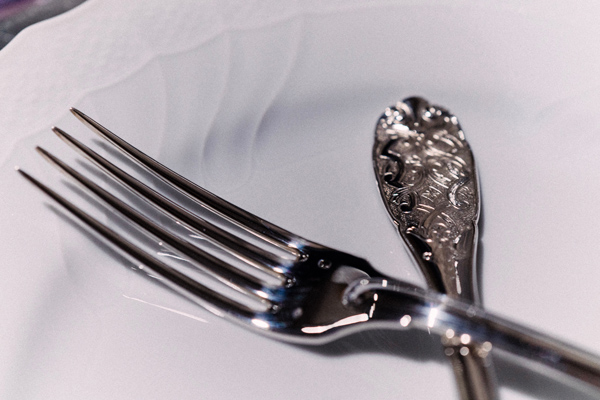 A closeup of a fork on an empty white plate