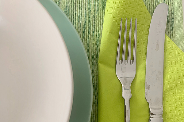 Green napkin with silver fork and knife sitting on top