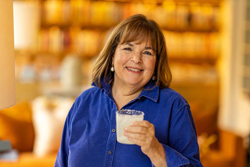 Ina Garten smiles at the camera from her home with a cocktail in her hand