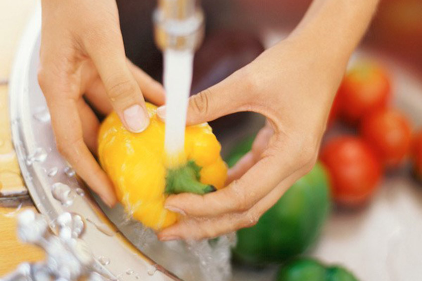 Hands washing a yellow bell pepper