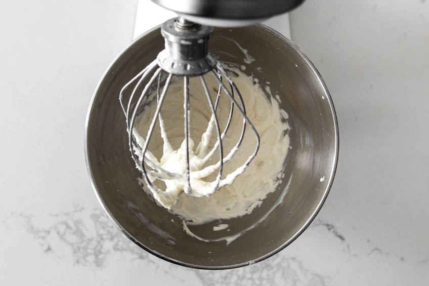 Cream cheese whipped cream being whipped in a metal bowl
