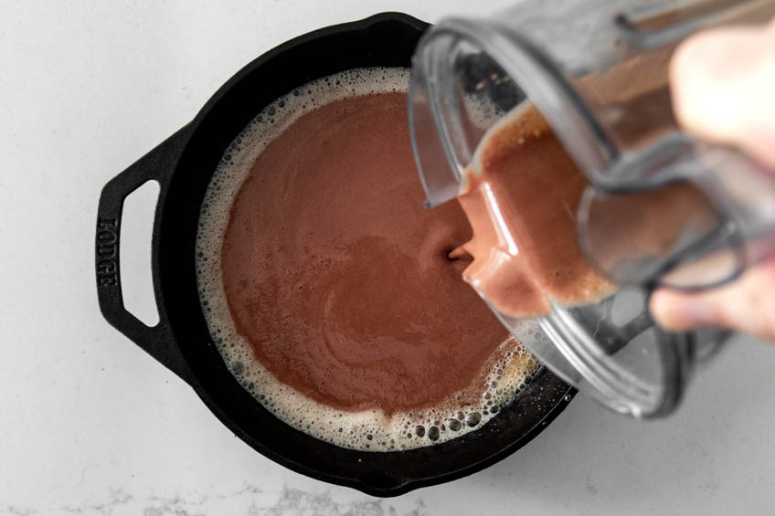 Batter for red velvet Dutch baby being poured into a cast iron pan