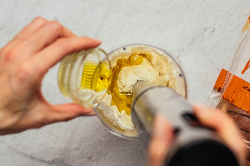 Olive oil being poured into whipped ricotta and blended