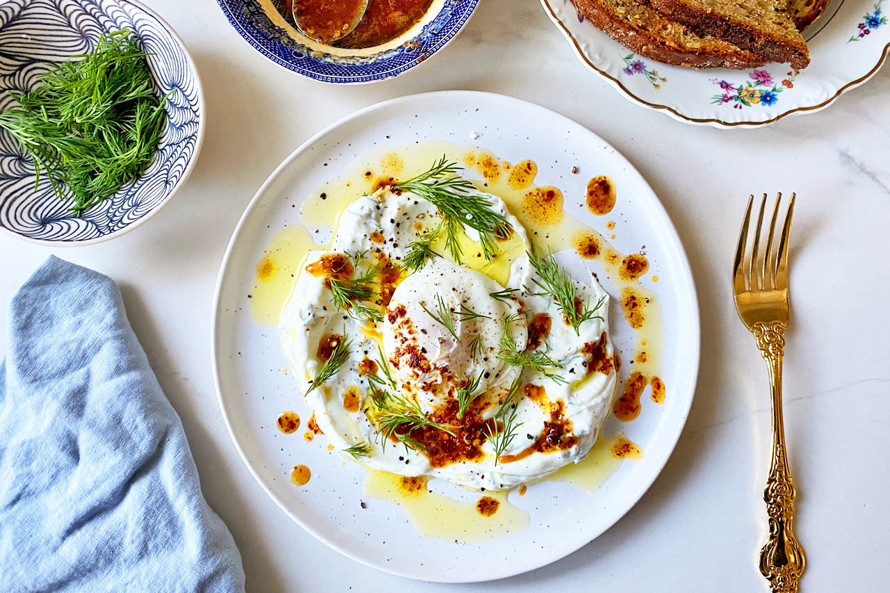 Turkish eggs drizzled with spiced butter sauce on a white plate.