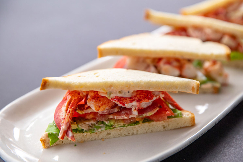 A lobster BLT sandwich made with lobster meat, bacon, lettuce and avocado on toasted white bread