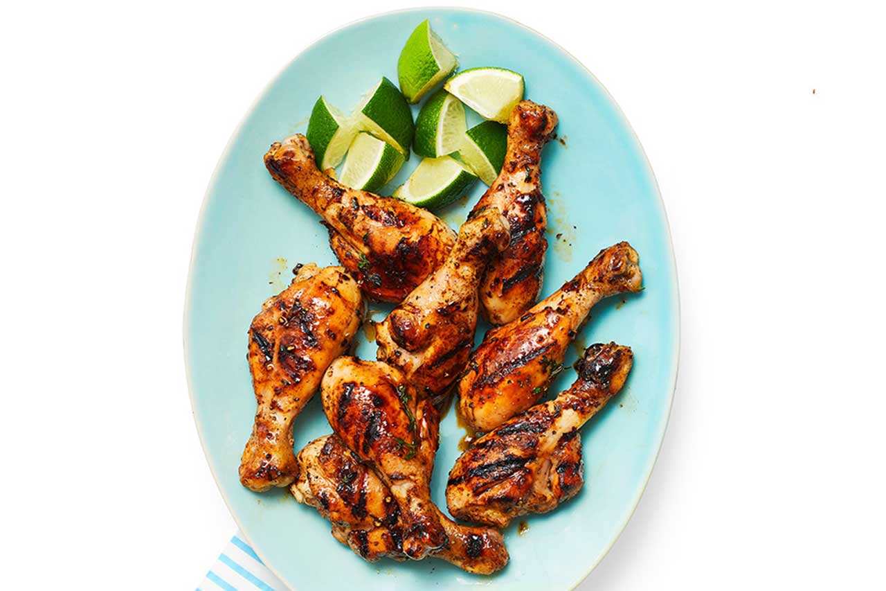 plate of grilled chicken drumstick with lime wedges