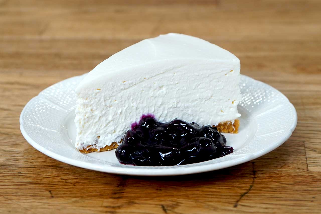 Slice of cheesecake on a plate with blueberry sauce
