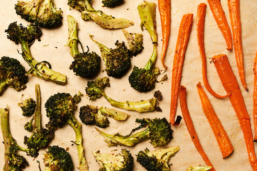 Roasted broccoli and carrots on a parchment-lined baking sheet