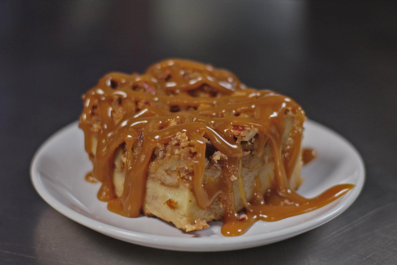 Bread pudding topped with bourbon caramel sauce served on a white plate