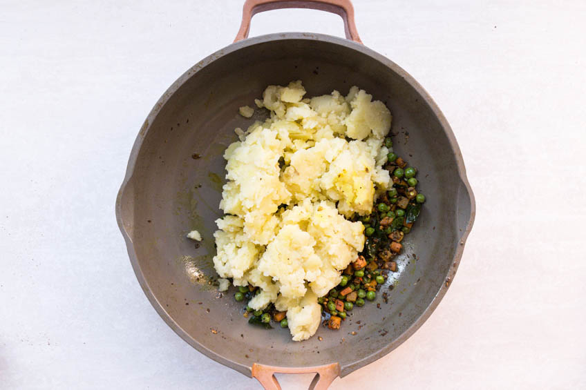 Mashed potatoes, spices, peas and carrots in a pan