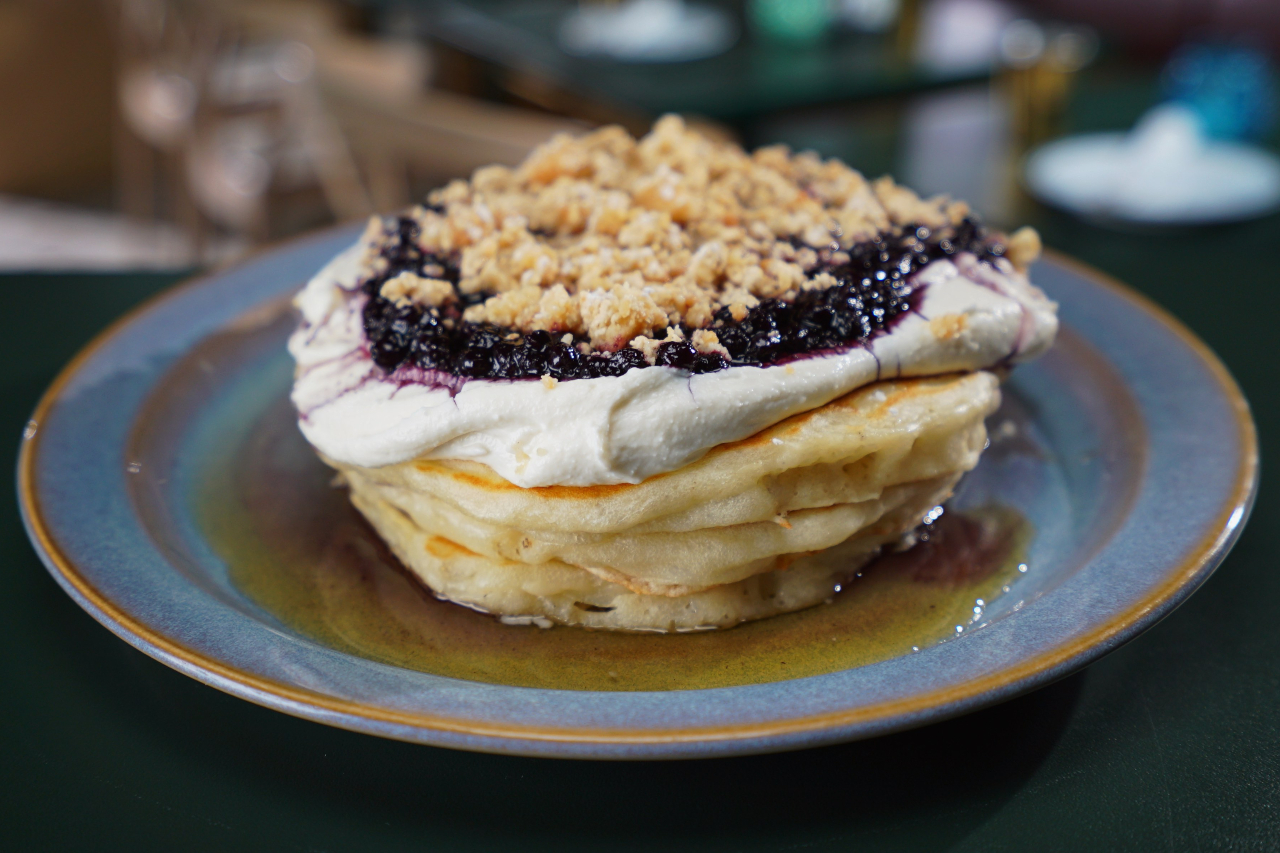 A stack of pancakes topped with ricotta, blueberry compote and halva