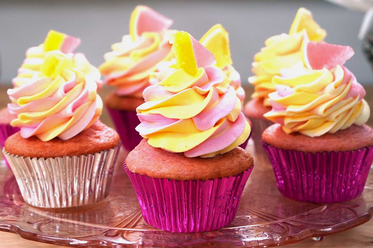 colourful decorated pink and yellow cupcakes on a tray